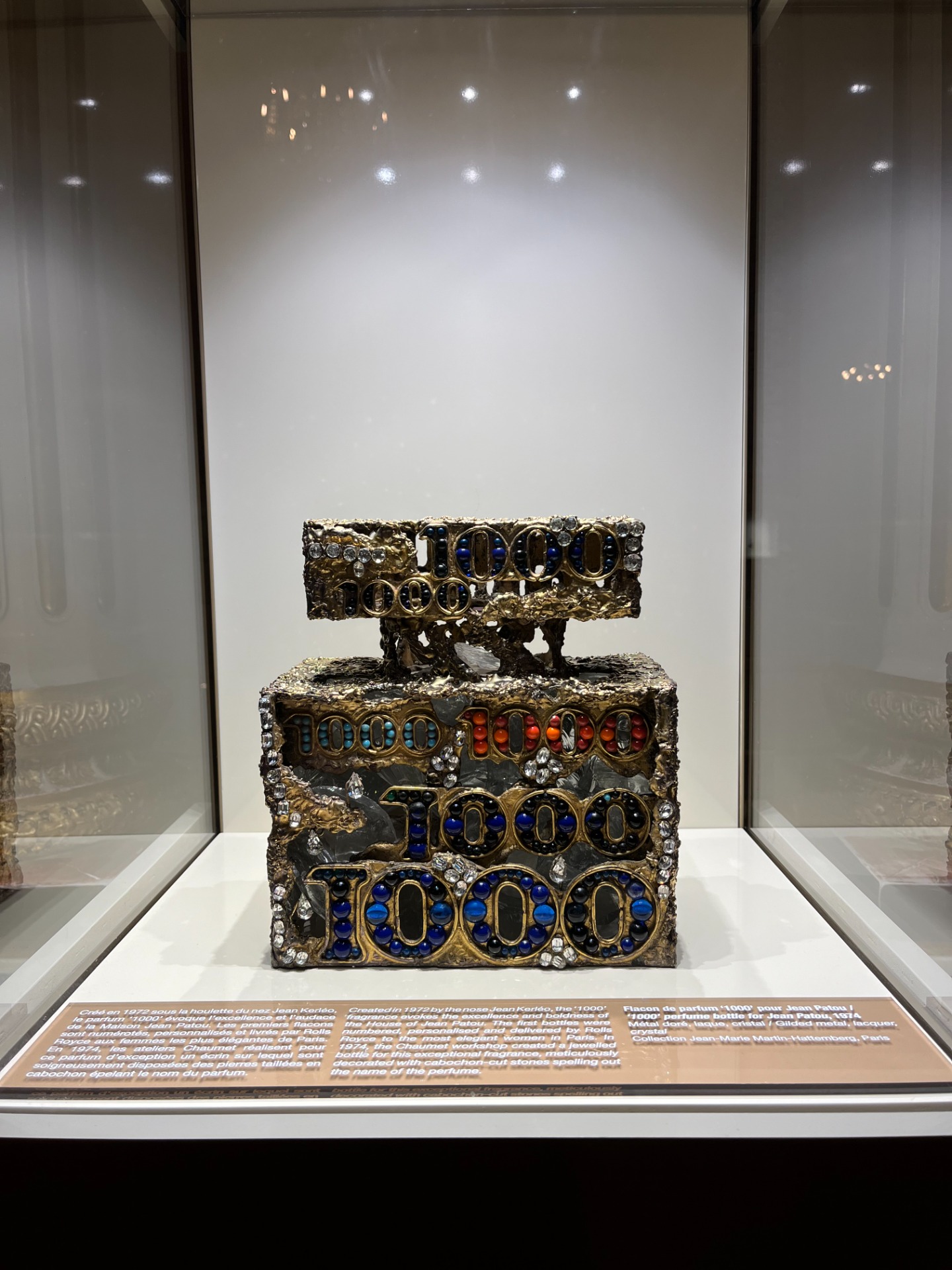 Flacon de parfum "1000" pour Jean Patou en métal doré, laque, cristal. Imaginé par le nez Jean Kerléo pour la Maison Jean Patou, le parfum "1000" évoque l'audace de la Maison. Les premiers flacons sont numérotés et livré par Rolls Royce. En 1974, les ateliers Chaumet réalisent ce somptueux flacon